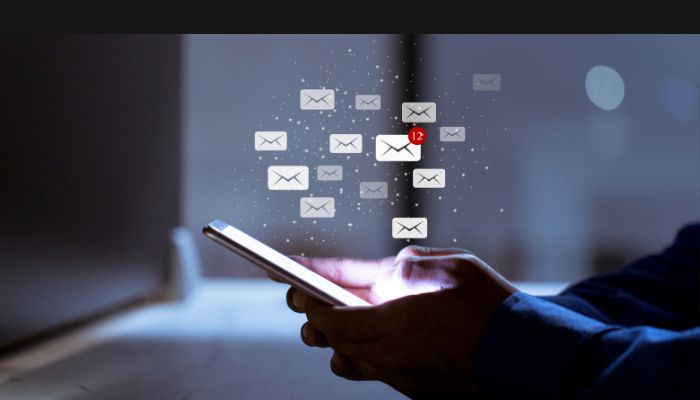 image of a person with their phone in their hand and cartoon graphics of many emails floating above the screen to show Best Sales Prospecting Emails