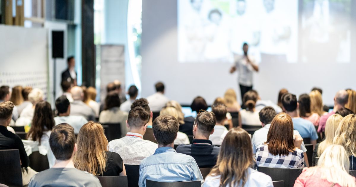 image of a speaker in front of an audience at a sales conference and text that says The Real Reason Your SKO Theme Fails (And How to Pick One That Sticks)